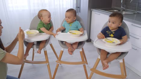 Mujer-asiática-alimentando-a-los-trillizos-de-niños-pequeños-Puree-en-casa