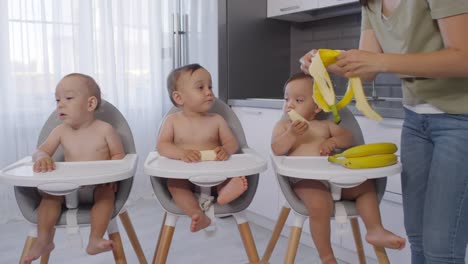Mujer-asiática-Peeling-Bananas-para-trillizos-bebé-en-casa
