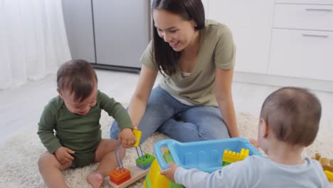 Asian-Mom-Comforting-Crying-Toddler-and-Sibling-Playing