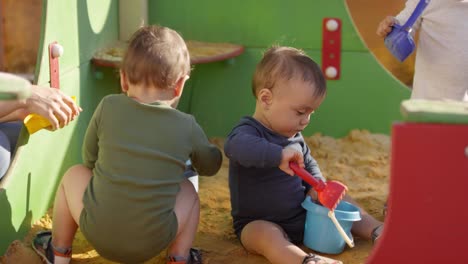 Drei-Kleinkinder-spielen-im-Freien-in-Sandgrube