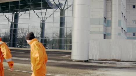 Two-construction-workers-in-orange-uniform-and-helmets-walking-tohether.-One-of-them-lost-his-helmet.-Having-fun