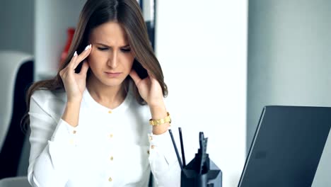 Tired-business-woman-at-workplace-in-office,-holding-her-head-in-hands.