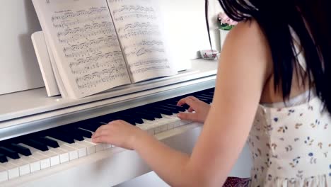 Young-brunette-woman-is-playing-the-piano-in-bright-room