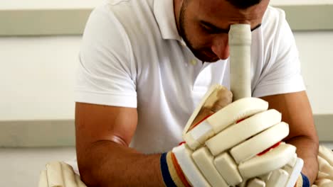 Cricketspieler-sitzen-auf-Bank-in-Umkleidekabine