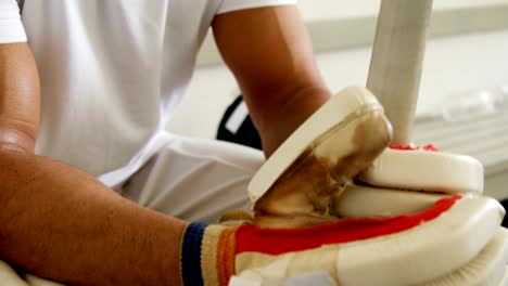 Cricketspieler-sitzen-auf-Bank-in-Umkleidekabine