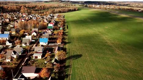 Hermoso-pequeño-pueblo-cerca-de-campo-verde-en-el-bosque-de-otoño.