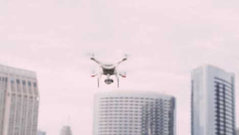 Quadcopter-drone-with-camera-on-gimbal-flying-in-the-city-sky,-shot-in-slow-motion