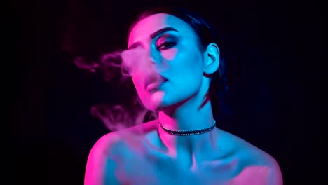 Gorgeous-brunette-woman-smoking-electronic-cigarette-in-neon-color-light