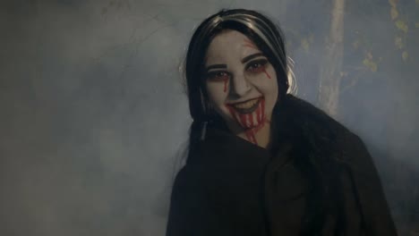 Bloody-evil-female-vampire-enjoying-the-foggy-halloween-night-in-the-woods-and-laughing