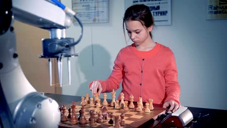 Junges-Mädchen-spielt-Schach-mit-einem-modernen-automatisierten-Schach-Roboter.-Kind-Genie-Konzept.-4K.