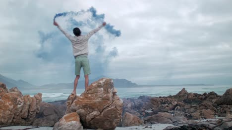 Man-playing-with-colour-smoke-grenade-at-the-beach