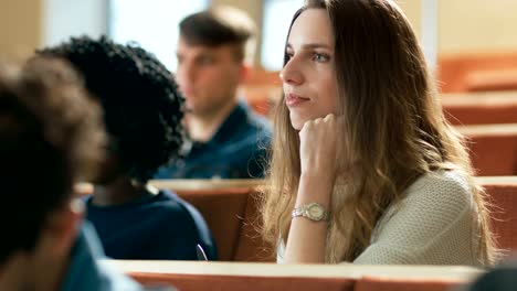 Beautiful-and-Intelligent-Young-Girl-Listens-to-a-Lecture-in-a-Classroom-Full-of-Multi-Ethnic-Students.-Shallow-Depth-of-Field.