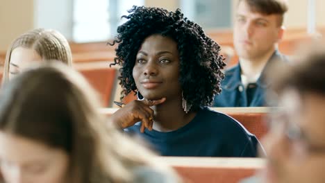 Smart-and-Beautiful-Young-Black-Girl-Listens-to-a-Lecture-in-a-Classroom-Full-of-Multi-Ethnic-Students.-Shallow-Depth-of-Field.