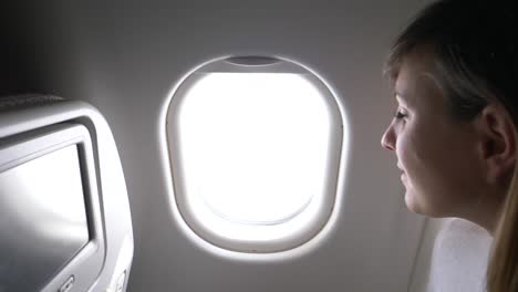 CLOSE-UP:-Woman-traveler-pulls-up-the-blinds-and-looks-through-airplane-window.