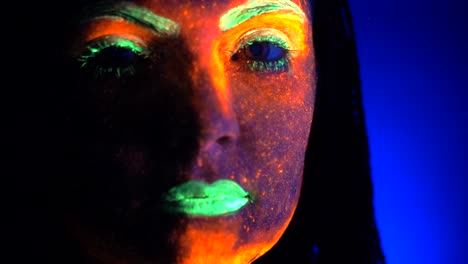 Close-up-portrait-of-fashion-model-woman-with-braids-in-neon-light.-Fluorescent-makeup-glowing-under-UV-black-light.-Night-club,-party,-halloween-psychedelic-concepts