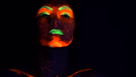 Fashion-sexy-dancer-with-braids-in-neon-light.-Fluorescent-makeup-glowing-under-ultraviolet-light.-Night-club,-party,-halloween-psychedelic-concepts.-Mysterious-woman-with-UV-painting