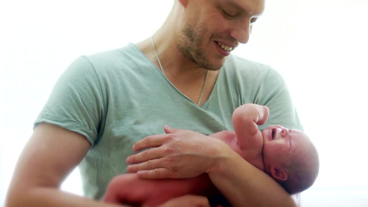 A Young Father Calms A Crying Newborn Baby. The Naked Child Is In The Hands Of An Athletic Man. Father's Day. Children's Day Free Stock Video Footage Download Clips Family