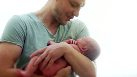 Der-Vater-beruhigt-das-Neugeborene.-Er-wiegt-und-hält-ihn-in-seinen-Armen.-Das-Kind-hat-Hunger,-essen-will,-nimmt-eine-Hand-in-den-Mund.-Stillzeit