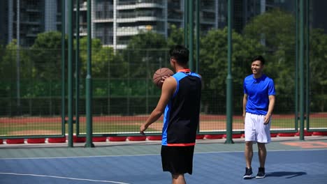 asiatische-junge-Erwachsene-spielen-Basketball-auf-Freiplatz