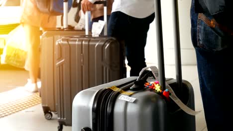 passenger-with-big-roller-luggage-standing-on-the-line-waiting-for-taxi-queue-at-taxi-parking-lot-at-airport-arrival-terminal