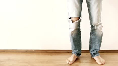 A-man-in-torn-up-jeans-stands-by-the-wall-and-stomps-with-his-foot