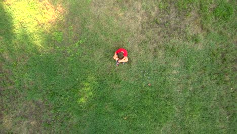 Little-boy-seated-alone-on-the-middle-of-a-field.-Sadness-concept.-Aerial-view.