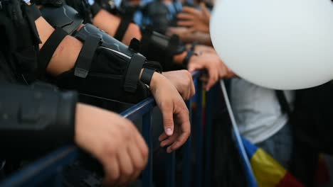 Polizist-die-Hände-auf-einen-Sicherheitszaun-während-eines-Aufstandes