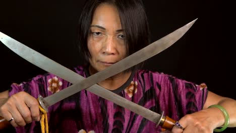 old-intimidating-asian-woman-crosses-swords-with-black-background