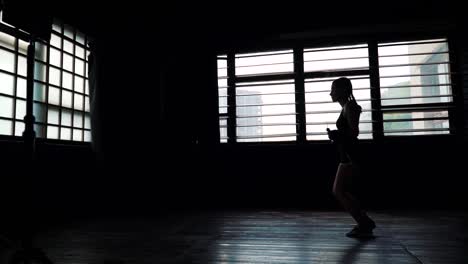 silhouette-young-purposeful-female-boxer-in-wrapped-bandage-hands-jumping-on-skipping-rope