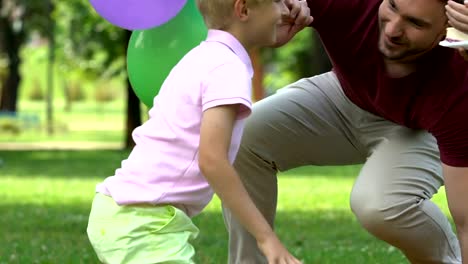 Loving-parents-congratulating-little-boy-on-birthday,-outdoor-party-in-park