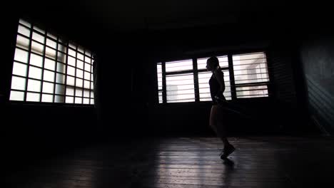 silhouette-young-purposeful-female-boxer-in-wrapped-bandage-hands-jumping-on-skipping-rope