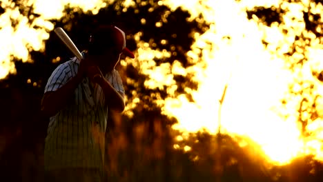 Práctica-de-béisbol-de-los-hombres-golpeando-una-pelota-de-béisbol-con-la-luz-del-atardecer