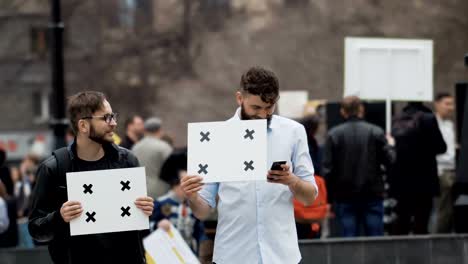 Leute-bei-der-Demo-mit-Banner-betrachten-das-Telefon.-Lächelnder-Mann-und-Handy.