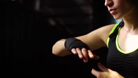 Closeup-panning-fit-woman-wrapping-hands-with-bandage-tape-preparing-for-boxing-training-slow-motion