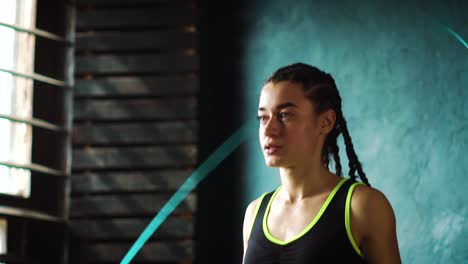 Slow-motion-young-serious-female-boxer-in-wrapped-hands-warming-up,-jumping-on-skipping-rope-closeup