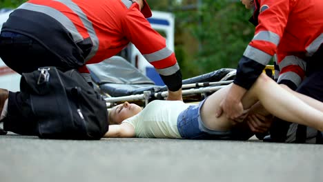 Ambulance-service-staff-taking-unconscious-girl-to-ambulance,-using-stretcher