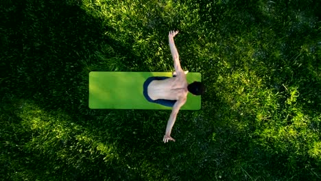 Professional-yoga-guy-practicing-yoga-in-park.-Top-view.-Drone-footage.