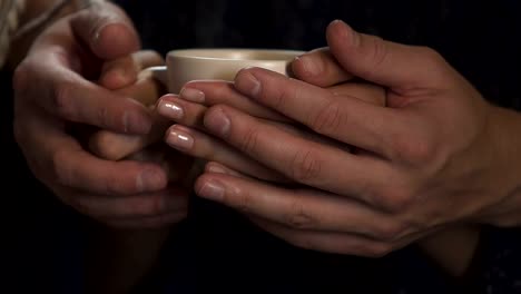 Männliche-und-weibliche-Hände-halten-Tasse-heißen-Kaffee-zusammen,-Fürsorge-für-Geliebte