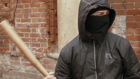 Portrait-of-bandit-with-mask-and-baseball-bat-on-brick-wall-background-.