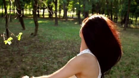 Close-up-of-a-happy-girl-with-flowing-hair-walking-in-a-summer-Park-at-sunset.