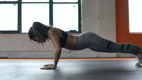 Hermosa-mujer-atlética-hace-flexiones-como-parte-de-su-cruzada-de-Fitness,-fisicoculturismo-gimnasio-rutina-de-entrenamiento.-Cámara-lenta.