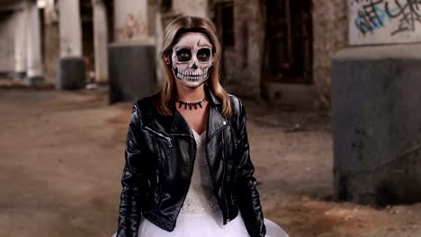 La-muchacha-en-un-vestido-de-novia-y-en-la-chaqueta-con-un-maquillaje-en-forma-de-una-calavera.