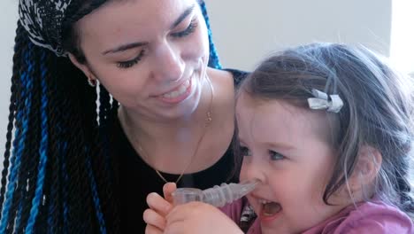 Little-cute-girl-inhaling-through-inhaler-mask-with-her-mom.-Use-nebulizer-and-inhaler-for-the-treatment.