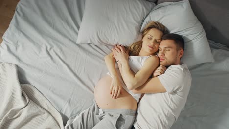 Feliz-joven-pareja-durmiendo-juntos-en-la-cama,-dulce-cariñosa-joven-personas-sosteniendo-mutuamente-mientras-dormir.-Hermosa-mujer-está-embarazada,-cariñosa-pareja-apoya-su-por-estar-allí-para-ella.