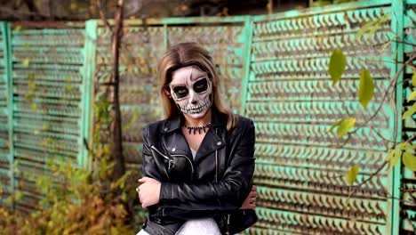 Creepy-bride-with-makeup-in-the-form-of-skull-on-the-background-of-an-old-fence.