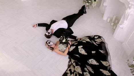 A-creepy-couple-with-makeup-for-Halloween-lie-on-the-floor-in-carnival-costumes