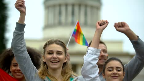 Activists-jumping-chanting-LGBT-slogans,-showing-painted-rainbow-symbols,-flags