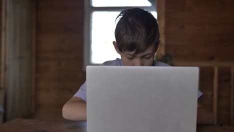 funny-boy-sitting-at-the-table-and-typing-on-a-laptop-very-quickly,-hacking