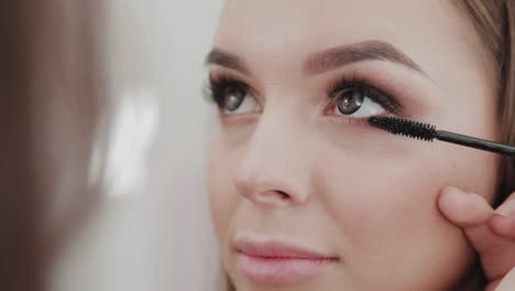 Professionelle-Make-up-Künstler-Frau-malt-Wimpern-an-Kunden-des-Schönheitssalons