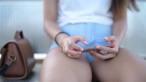 Hands-Of-Young-Woman-Using-Phone-While-Sitting
